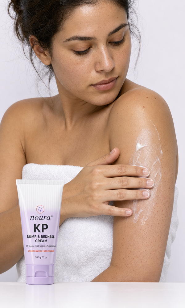 Woman in a towel smoothing Noura KP cream onto her upper arm after a shower