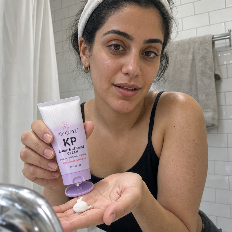 Woman in a headband holding Noura cream with a dab of cream in her palm