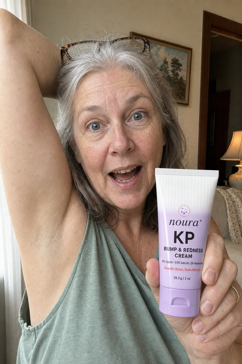 Woman with gray hair raising one arm and holding a tube of Noura KP cream